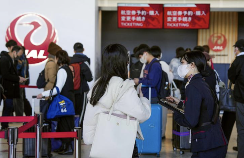 A staff member of japan airlines helps customers at osaka international airport